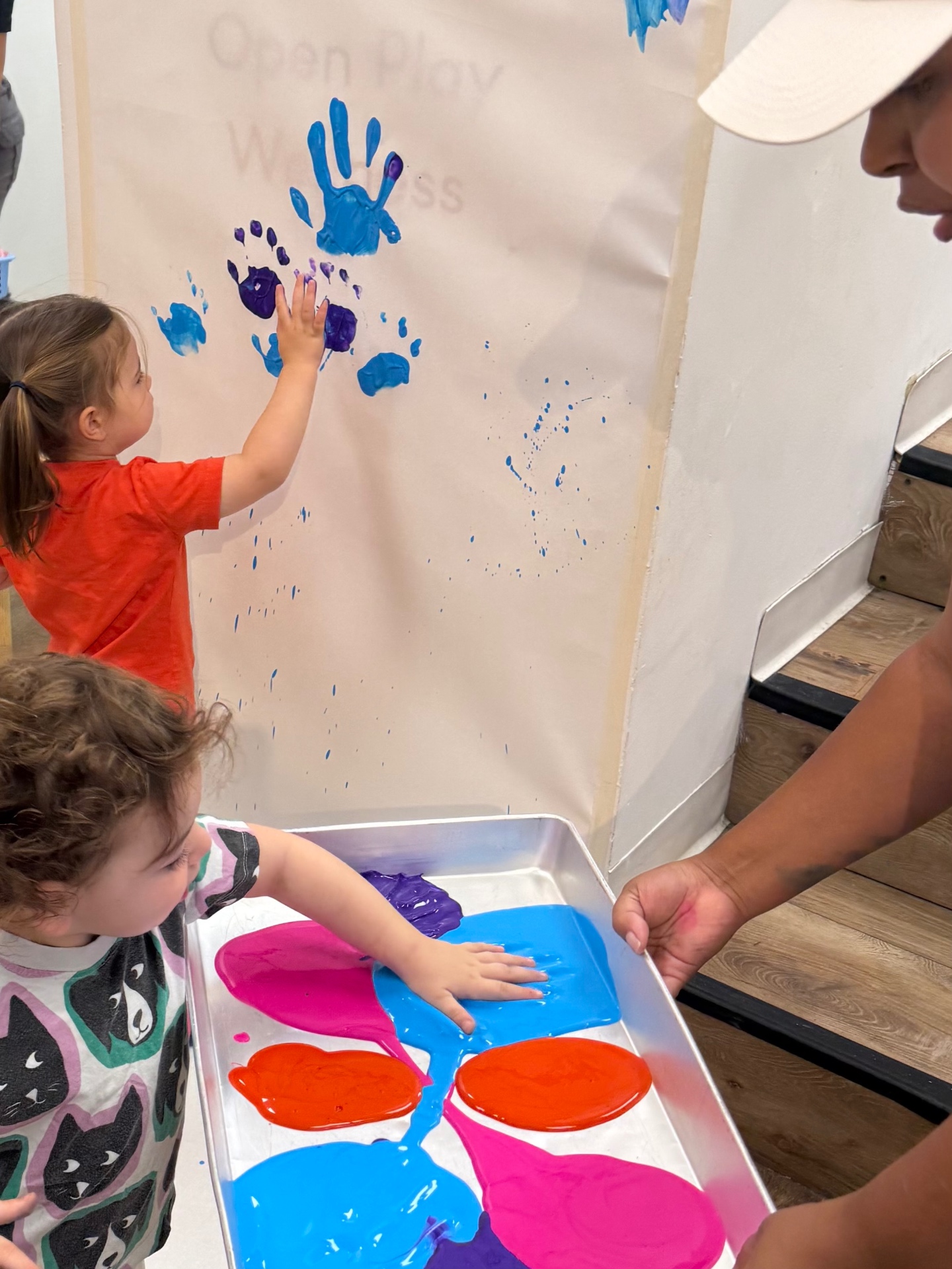 Toddlers making colorful handprint art