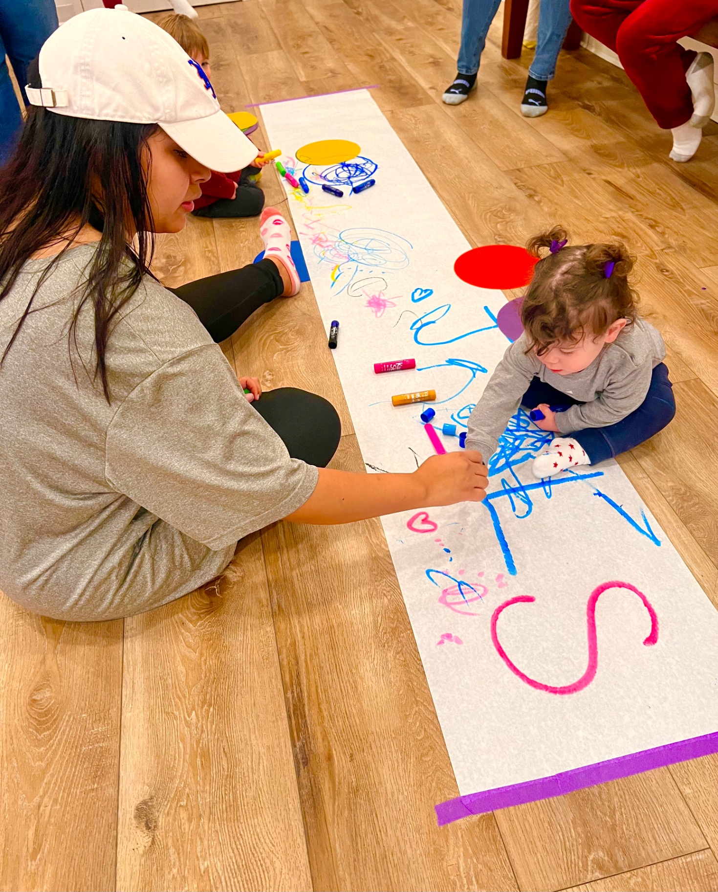 Kids drawing on a long paper roll on the floor