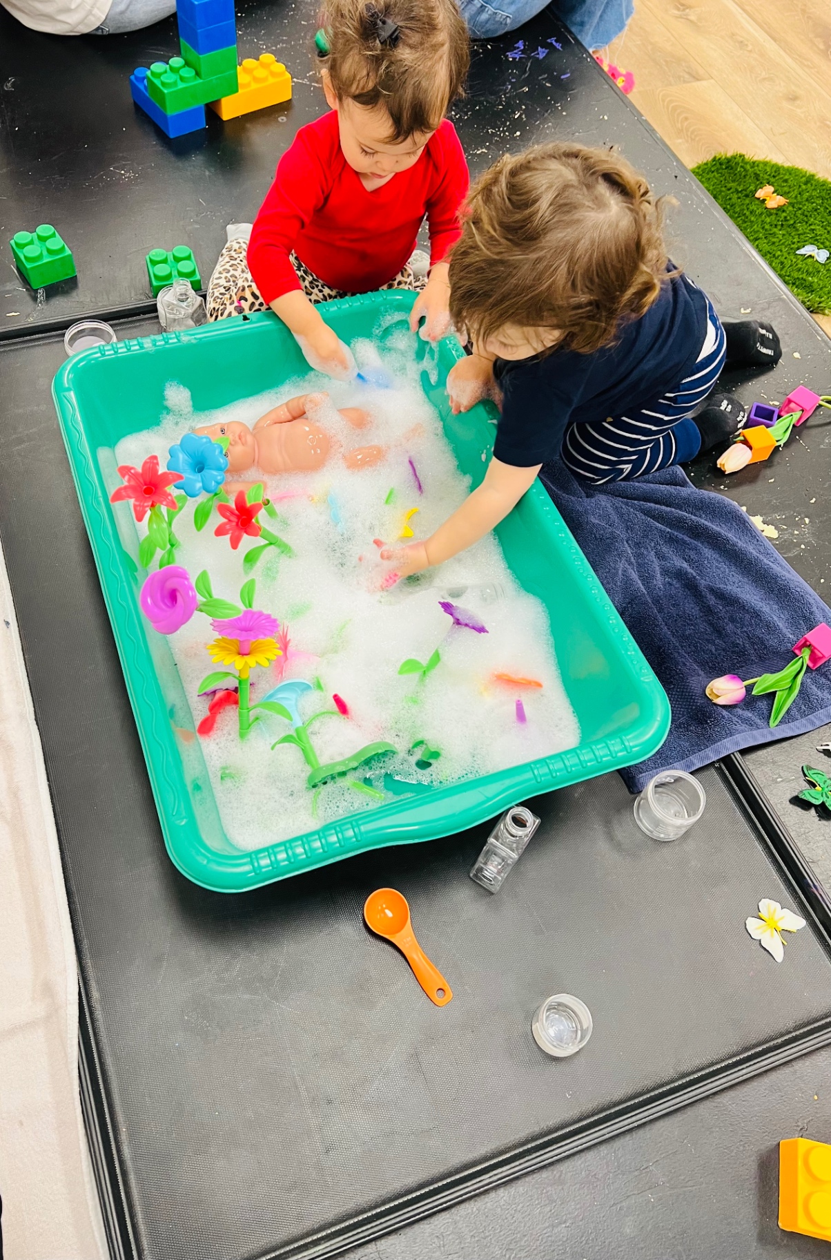 Kids playing with bubbles and flowers in a sensory bin